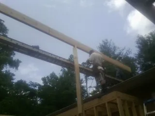Carpenter setting a ridge beam over a new addition frame — Ice Dam Removal by Roofing Brothers in Pittsford