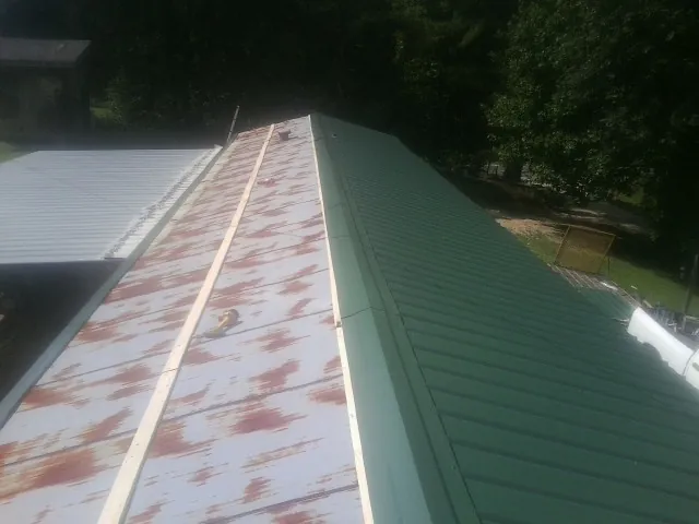 Old rusted panels beside newly installed green metal roofing — Wind Damage Roof Repair by Roofing Brothers in Pittsford