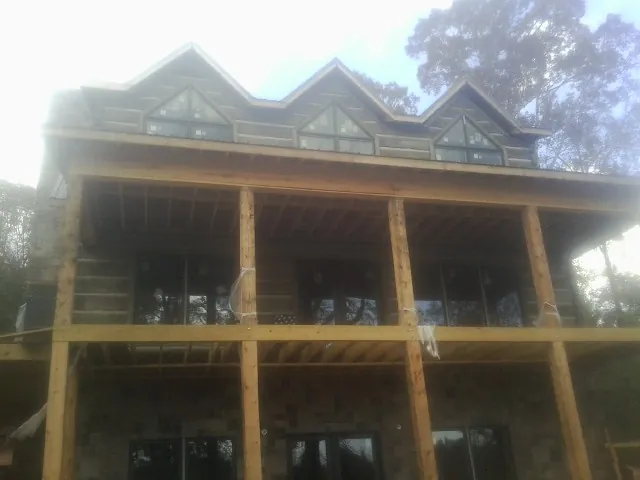 Dormers and porch framing on a large log home under construction — Roof Coating work by our crew in Pittsford