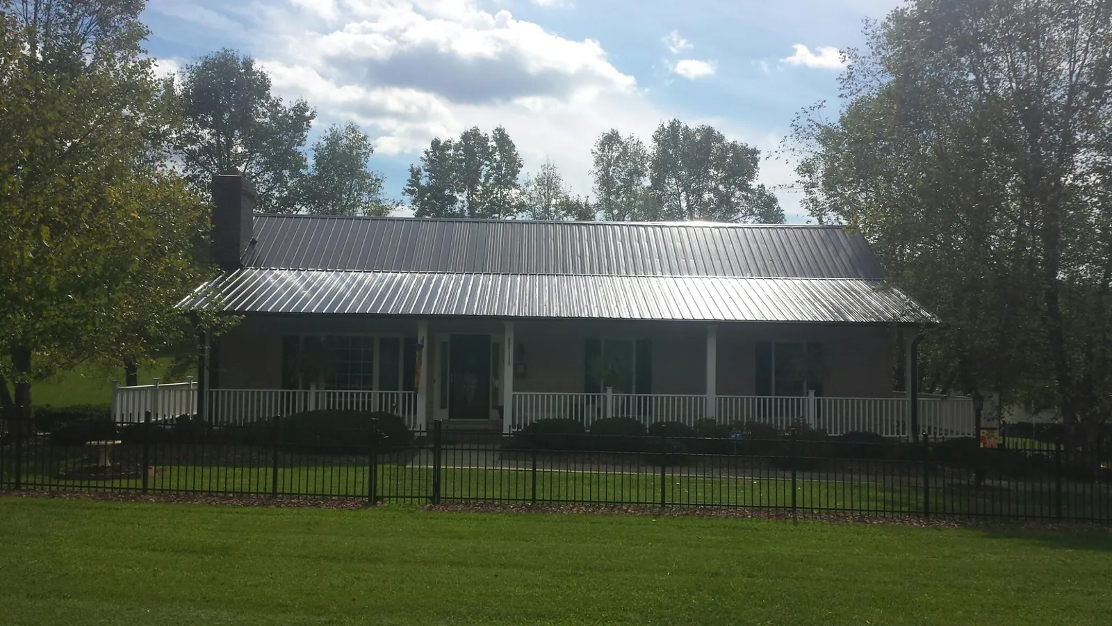 Gray metal roof on a brick ranch with a full width front porch — Gutter Guard Installation work by our crew in Pittsford