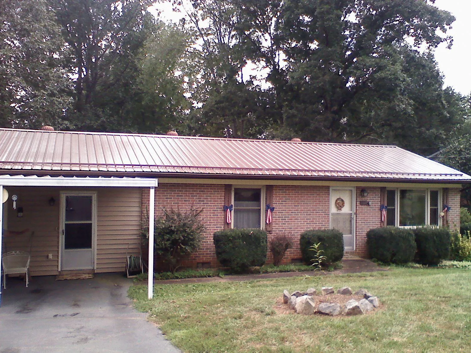 Bronze metal roof and carport on a brick ranch home — Roof Repair work by our crew in Pittsford
