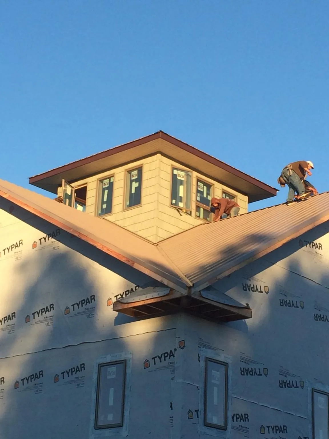 Roofers working around a rooftop cupola on a new metal roof at sunset — Roof Waterproofing in Pittsford by Roofing Brothers
